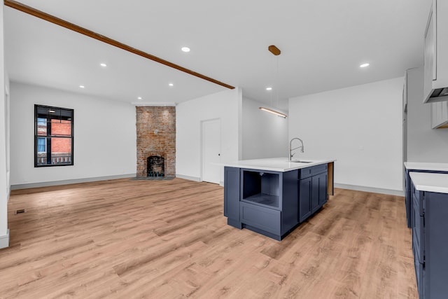 kitchen featuring light countertops, blue cabinetry, a fireplace, and a sink