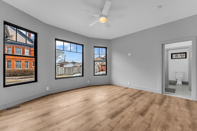 spare room with light wood-style floors, baseboards, visible vents, and ceiling fan