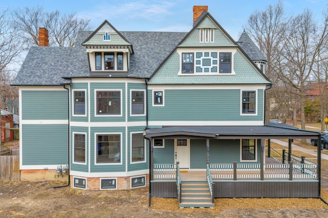 victorian house featuring a porch and a chimney