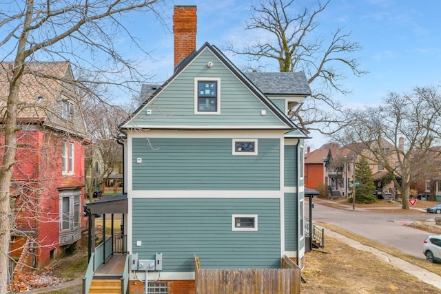 rear view of property featuring roof with shingles and a chimney