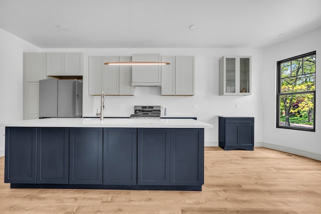 4301 Avery St, Detroit, MI 48208 - kitchen featuring stainless steel appliances, a kitchen island with sink, light countertops, light wood finished floors, and baseboards