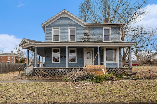 view of front facade featuring covered porch, fence, and a chimney