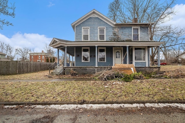 view of front of property featuring covered porch, fence, and a chimney