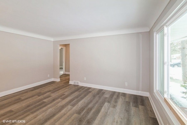 unfurnished room with wood finished floors, visible vents, and baseboards