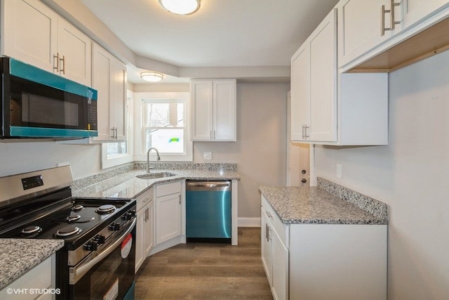 kitchen featuring appliances with stainless steel finishes, a sink, light stone counters, and white cabinets