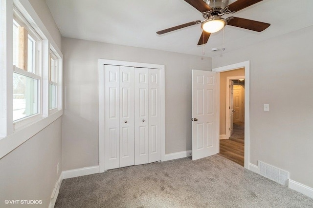 unfurnished bedroom featuring a closet, visible vents, a ceiling fan, carpet flooring, and baseboards