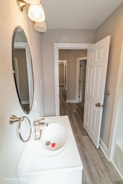 bathroom with vanity, wood finished floors, a bath, and baseboards