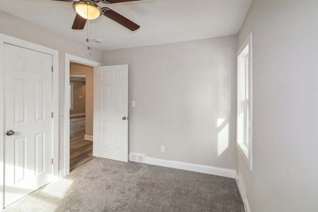 unfurnished bedroom with visible vents, multiple windows, baseboards, and carpet flooring