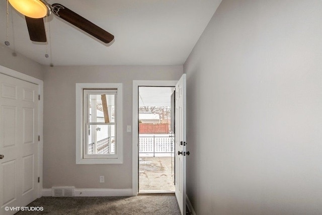 doorway with carpet floors, baseboards, visible vents, and ceiling fan