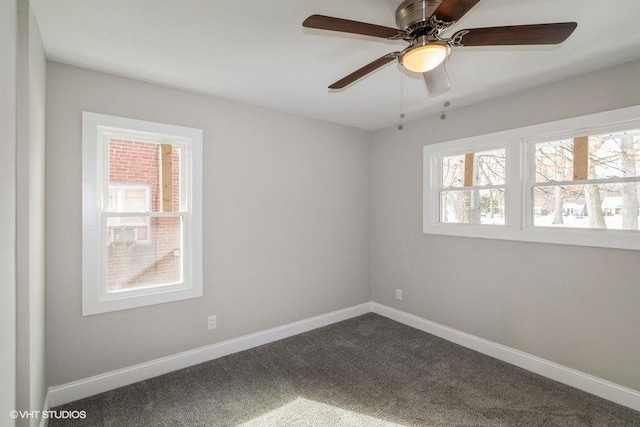 empty room featuring dark carpet, baseboards, and ceiling fan