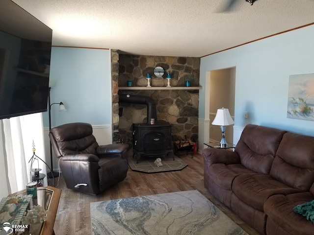 living room with a wood stove, crown molding, a textured ceiling, and wood finished floors