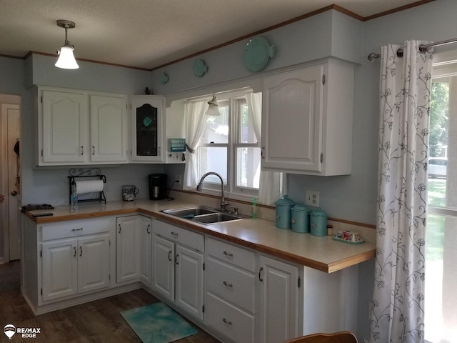 kitchen featuring ornamental molding, dark wood finished floors, white cabinetry, and a sink