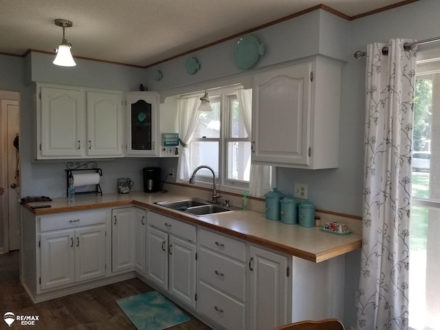 kitchen with crown molding, a sink, light countertops, white cabinetry, and dark wood-style floors