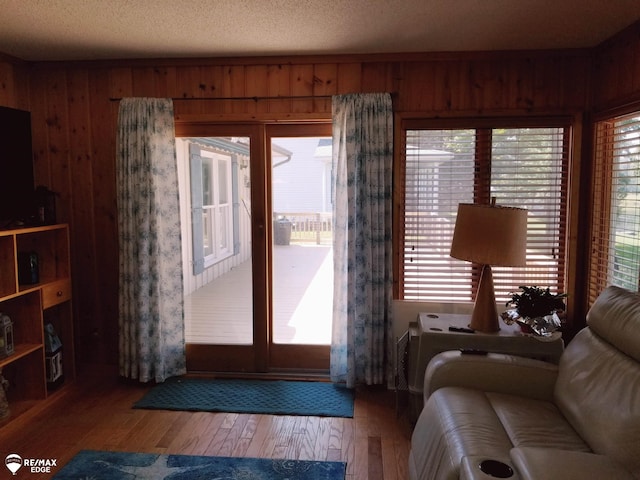 doorway to outside featuring a textured ceiling, wood walls, and wood-type flooring