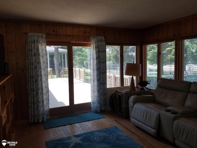 living area with plenty of natural light, wood walls, and hardwood / wood-style flooring