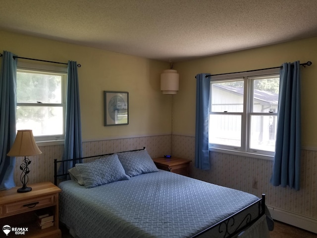 bedroom with a baseboard radiator, a wainscoted wall, a textured ceiling, and wallpapered walls