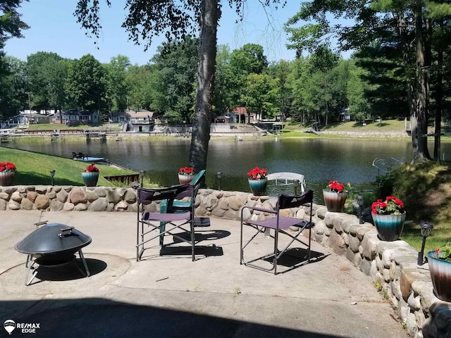 view of community featuring a water view, a patio area, and a fire pit