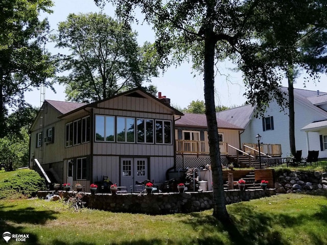 rear view of property with stairway, a wooden deck, a lawn, and a chimney