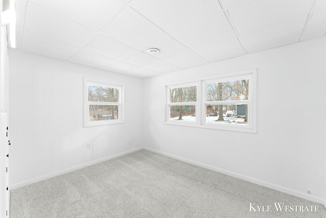 empty room with a paneled ceiling, carpet flooring, and baseboards