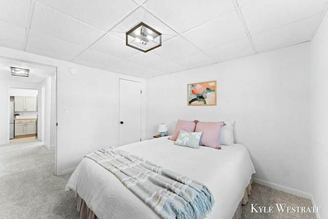 bedroom with freestanding refrigerator, a drop ceiling, light carpet, and baseboards