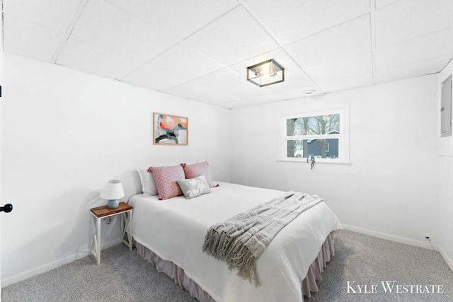 carpeted bedroom featuring a drop ceiling and baseboards