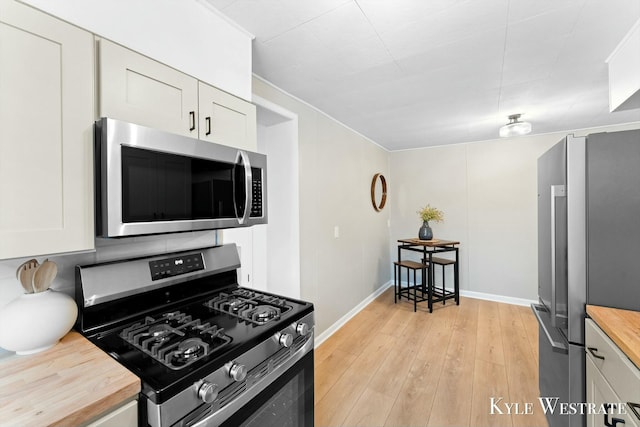 kitchen featuring appliances with stainless steel finishes, butcher block countertops, white cabinets, and light wood-style floors