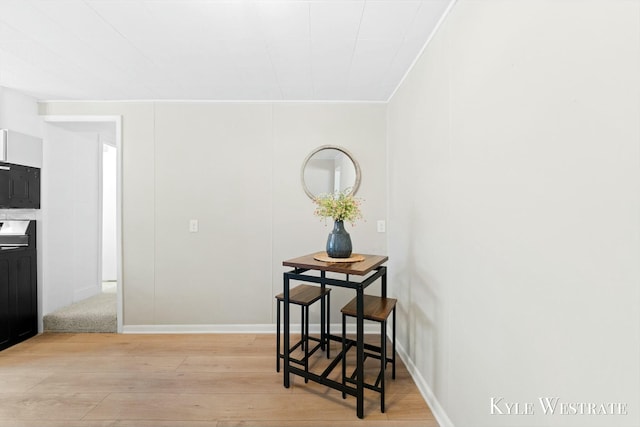 dining space featuring ornamental molding, light wood-style flooring, and baseboards