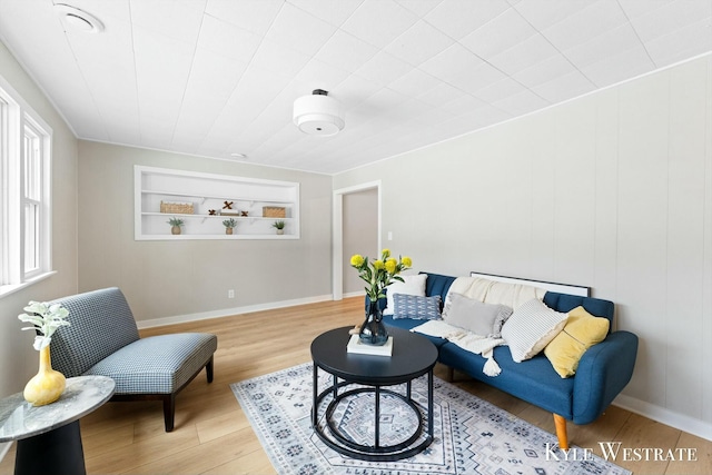 living area with built in features, baseboards, and wood finished floors