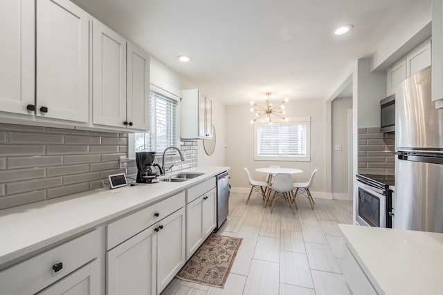 kitchen featuring appliances with stainless steel finishes, decorative backsplash, a sink, and light countertops