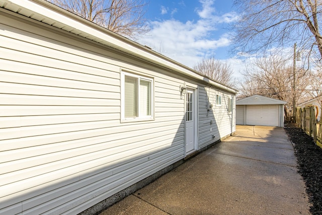 view of side of property featuring driveway, an outdoor structure, fence, and a detached garage