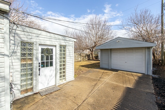 detached garage featuring driveway and fence