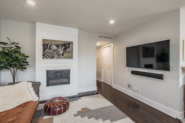 living area with dark wood-style floors, visible vents, a fireplace, and baseboards