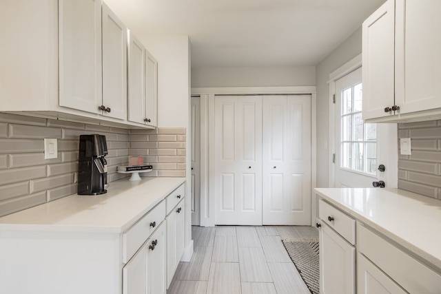 kitchen featuring white cabinets, light countertops, and backsplash