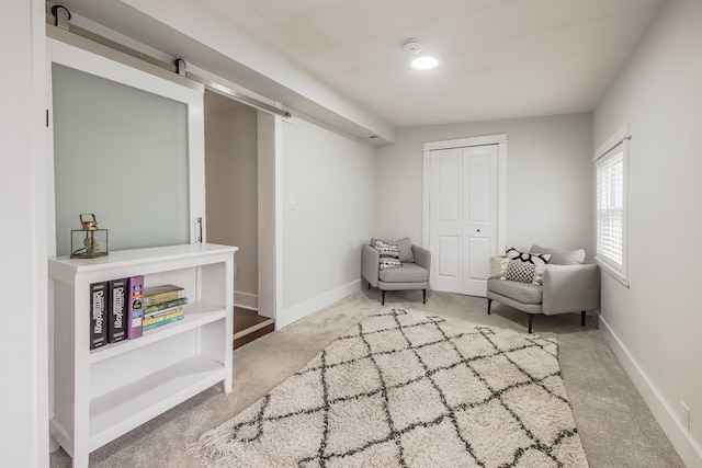 living area featuring carpet floors, baseboards, and a barn door