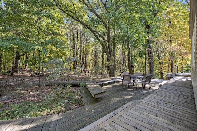 wooden deck featuring outdoor dining area and a wooded view