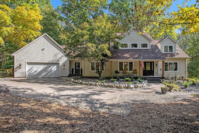 view of front of house featuring a garage, covered porch, driveway, and roof with shingles