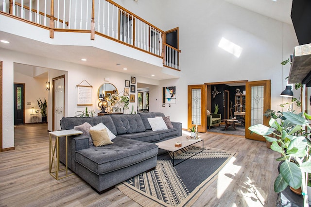 living room featuring wood finished floors, a towering ceiling, and recessed lighting