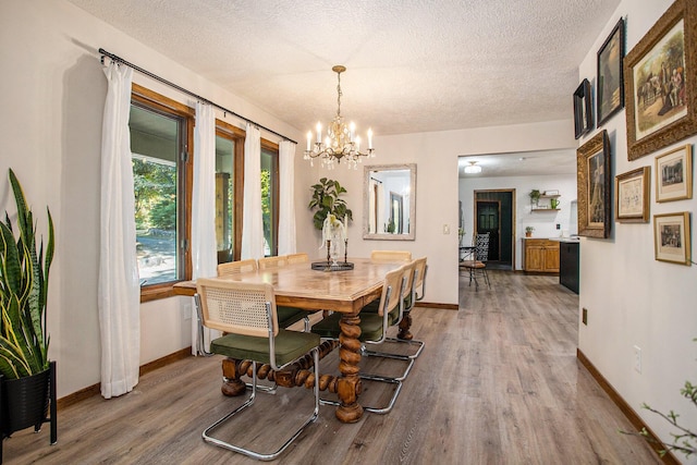 dining area featuring a chandelier, a textured ceiling, and light wood finished floors