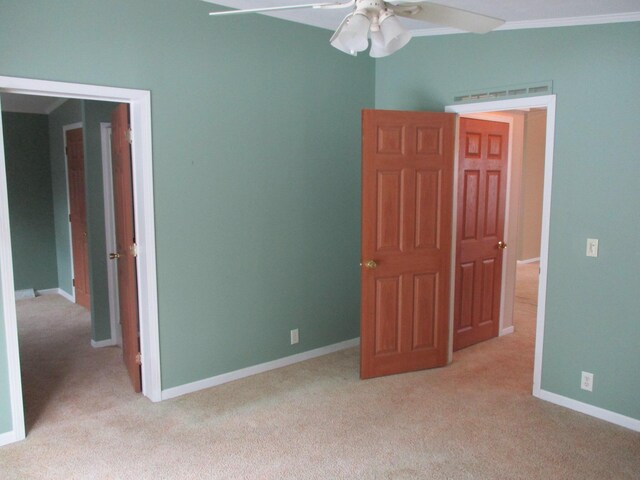 unfurnished room with ornamental molding, light carpet, ceiling fan, and baseboards