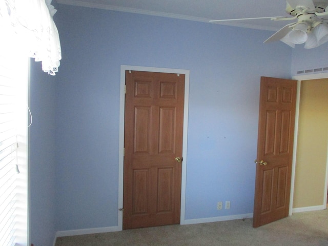 unfurnished bedroom with crown molding, carpet floors, visible vents, and baseboards