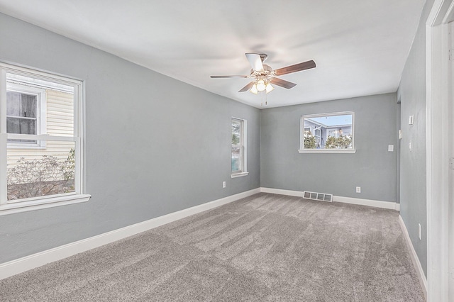 carpeted spare room with baseboards, visible vents, and a ceiling fan