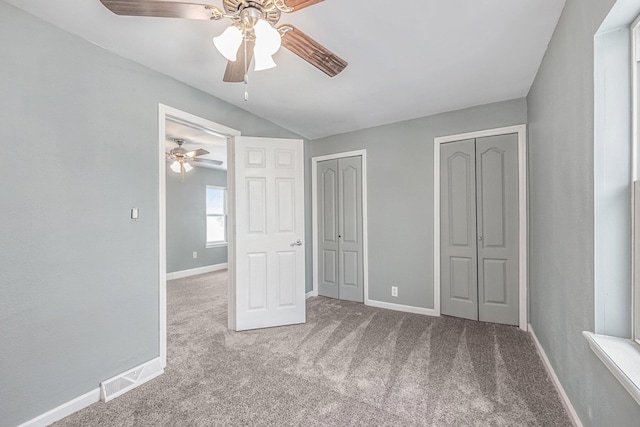 unfurnished bedroom featuring baseboards, multiple closets, and carpet flooring