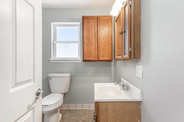 half bathroom with toilet, vanity, and baseboards