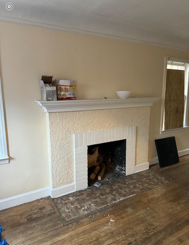 room details featuring a brick fireplace, crown molding, baseboards, and wood finished floors