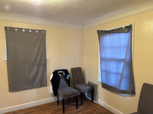 sitting room with a textured ceiling, crown molding, wood finished floors, and baseboards