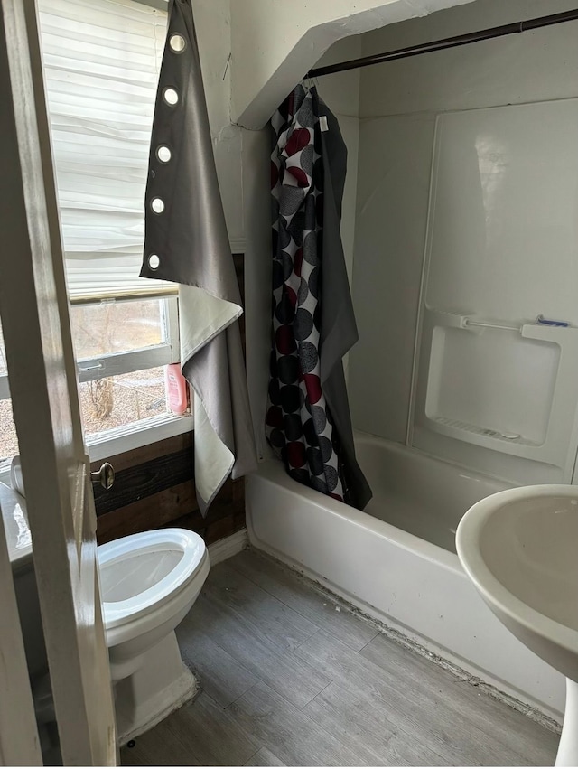 full bathroom with a sink, shower / tub combo with curtain, toilet, and wood finished floors