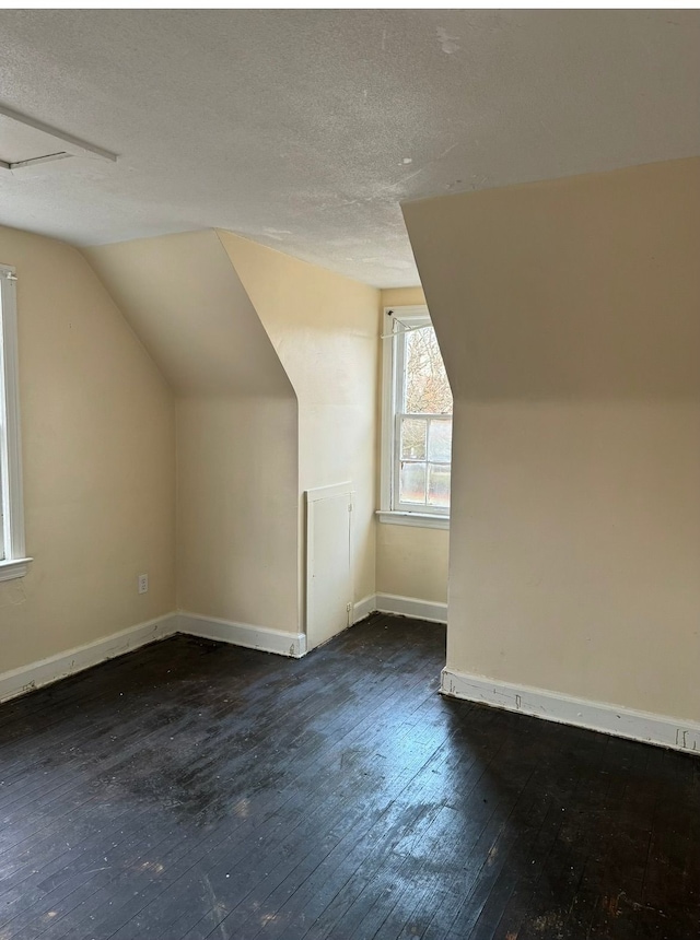 bonus room featuring baseboards, vaulted ceiling, a textured ceiling, and hardwood / wood-style floors