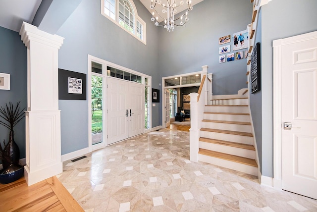 entryway with stairs, a chandelier, visible vents, and ornate columns