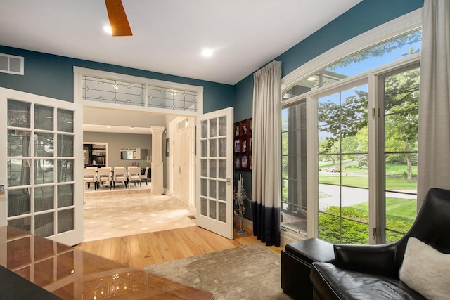 sitting room with wood finished floors, visible vents, french doors, plenty of natural light, and ornate columns