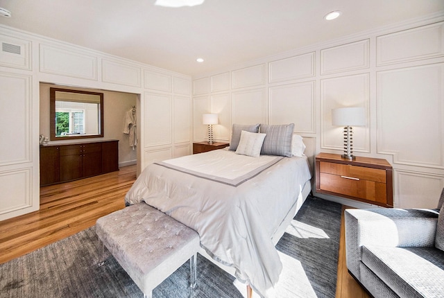 bedroom with crown molding, recessed lighting, visible vents, a decorative wall, and light wood-type flooring